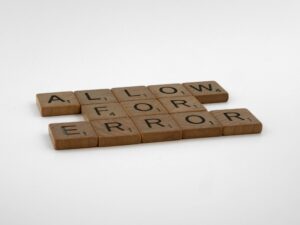 Scrabble tiles spelling 'Allow For Error' on a white background, symbolizing flexibility and acceptance.