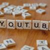 Wooden letter tiles spelling 'YOUTUBE' on a wooden surface, symbolizing video sharing and streaming.