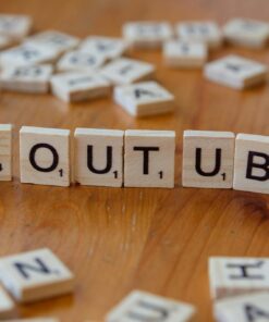 Wooden letter tiles spelling 'YOUTUBE' on a wooden surface, symbolizing video sharing and streaming.