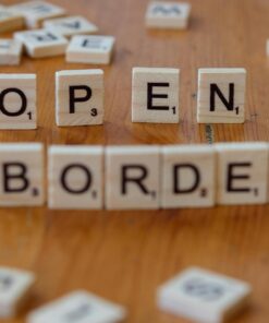 Wooden Scrabble letters on a table spelling out 'open border', concept of migration and geopolitics.
